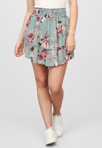 Sukňa s kvietinovým vzorom v svetlomodrej farbe s vrstvenými ruffles. Má gumičkový pás pre pohodlie. Tkanina pôsobí ľahko a vzdušne.