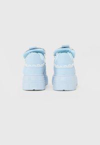 Niebieskie sneakersy z masywną gumową podeszwą, falistymi akcentami i wyściełanym kołnierzem. Gładki materiał, okrągły nosek i płaski wzór bieżnika.
