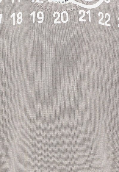 Maglione grigio lavorato a maglia con grandi numeri bianchi da 17 a 22 disposti ad arco vicino al collo.