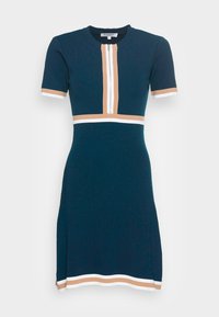 Robe côtelée bleu marine à manches courtes, avec une fermeture éclair centrale et des rayures horizontales en blocs de couleur blanc et beige au niveau de la poitrine et de l'ourlet.