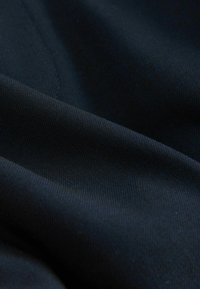 Tessuto di un blu navy con una trama sottile e testurizzata. Il materiale appare morbido e leggermente teso, mostrando variazioni alla luce.