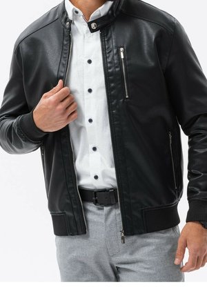 Czarna skórzana kurtka z zamkiem z przodu i stojącym kołnierzem. Posiada boczne kieszenie oraz ribbowe mankiety. Nosi się ją na białej koszuli.