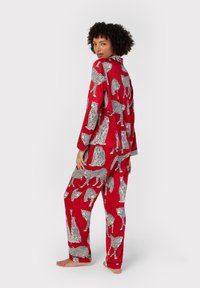 Red pajama set made of soft fabric featuring black and white leopard patterns. The top has a collar, and the pants are loose-fitting.
