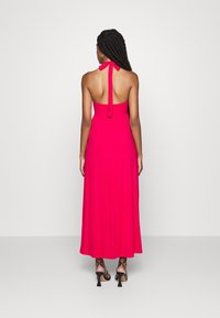 Maxikleid aus leuchtend pinkem Stoff. Halsband-Design mit offener Rückseite und Ripsband zum Binden. Fließende Silhouette mit glatter Textur.