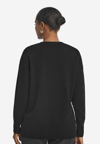Schwarzer, übergroßer Pullover mit geripptem Saum und Bündchen. Weiches Strickmaterial, runder Ausschnitt und tief sitzende Schulternähte.