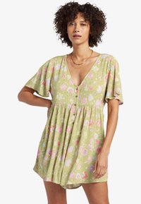 Vestido mini floral en tela verde claro, con un profundo escote en V, mangas cortas acampanadas, cierre frontal de botones y estampados en rosa y púrpura.