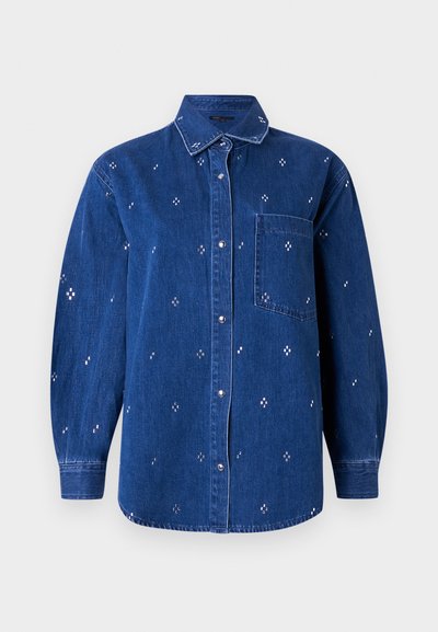 Chemise en denim bleu à boutons, manches longues, col, poche poitrine et petit motif brodé en forme de croix blanche réparti sur toute la surface.