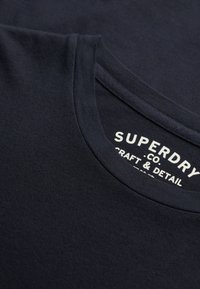 Navyblauwe katoenen t-shirt met een ronde hals, een gladde textuur en een wit gedrukt label met "Superdry," "Craft & Detail."