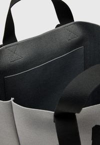 Borsa in tessuto con un design nero e grigio, materiale testurizzato, interno spazioso e una tasca interna per l'organizzazione.