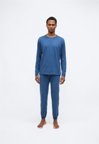 Blå langærmet top og matchende bukser lavet af blødt stof. Toppen har en rund halsudskæring og broderet logo; bukserne har elastiske manchetter.