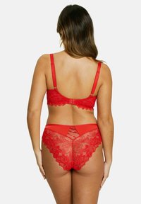 Ensemble de soutien-gorge et culotte en dentelle rouge avec motifs floraux, bords festonnés, et détails en croix sur la taille et le dos du soutien-gorge.
