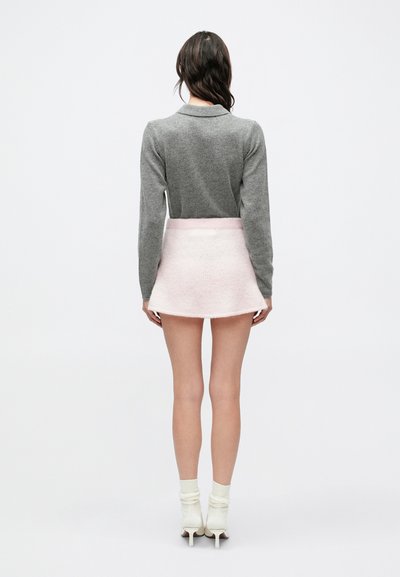 Šedý sveter s dlhou rukávou, mäkká pletená štruktúra. Svetloružová zvonová mini sukňa s chlpatou textúrou. Biele čižmy na opätku v kombinácii s rebrovanými ponožkami.