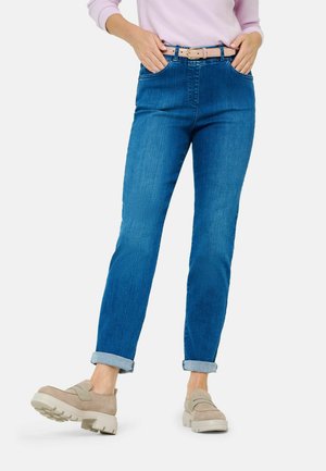 Blaue Jeans mit geradem Bein, ausgestattet mit einem hellen Gürtel und aufgerollten Säumen, kombiniert mit beigen Plateauschuhen.