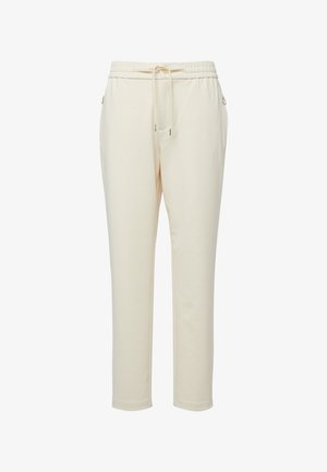 Kremowe spodnie dresowe o zwężanych nogawkach, z elastycznym pasem, regulowanym sznurkiem i zapinanymi na zamek kieszeniami bocznymi.