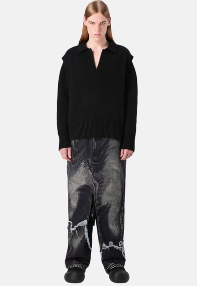 Schwarzer gestrickter Pullover mit Kragen und geripptem Saum, kombiniert mit hoch taillierten, verwaschenen schwarzen Jeans mit einem einzigartigen Muster und Schlitzen.