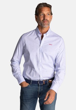 Lichtblauw overhemd met kleine rode en blauwe spikkels, voorzien van een klassieke kraag en lange mouwen, gecombineerd met blauwe jeans en een riem.