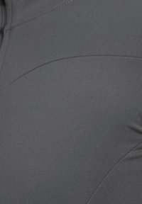 Grijs, elastisch sporttop met een gladde textuur. Beschikt over gebogen naden en een aansluitend ontwerp, geschikt voor actieve kleding. Geen zichtbare hardware of patronen.