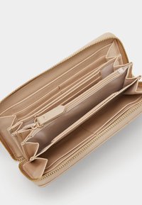 Cartera de cuero beige con cierre de cremallera. El interior cuenta con múltiples ranuras para tarjetas, compartimentos y un bolsillo con cremallera para monedas.