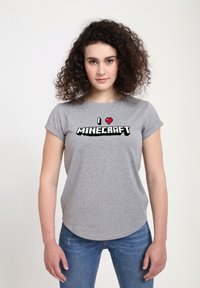 Šedé tričko s krátkým rukávem s grafikou "I �♥ MINECRAFT" v černém a červeném pixelovém písmu a zaobleným lemem.