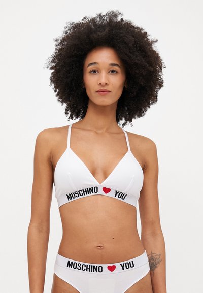 Bralette blanco y ropa interior a juego con una banda negra que presenta corazones rojos y texto "MOSCHINO YOU". Diseño triangular, tirantes finos.