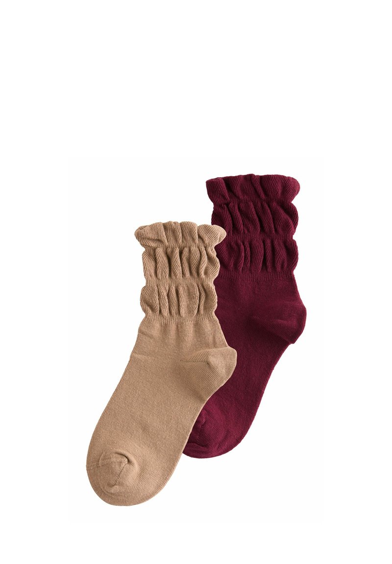 Due coppie di calzini alla caviglia: una in beige con un bordo a coste e l'altra in bordeaux scuro, caratterizzata da una texture arricciata.