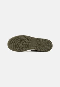 Nike sneakersula i olivgrön gummi, med ett cirkulärt mönster, texturerade greppsektioner och en synlig logotyp på mellansulan.
