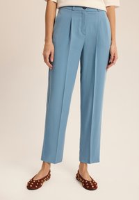 Jasnoniebieskie spodnie o wysokim stanie z zakładkami, g ładką fakturą i dopasowanym krojem. Noszone z bordowymi balerinami z złotymi zdobieniami.