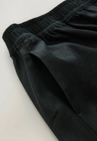 Zwarte stof korte broek met een elastische tailleband, een zachte textuur en een eenvoudig ontwerp zonder zichtbaar patroon of accenten.