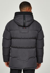 Donkergrijze gewatteerde jas met een zwarte capuchon, met horizontale secties, een esdoornbladaccent op de achterkant en een logo op de nekgordel.
