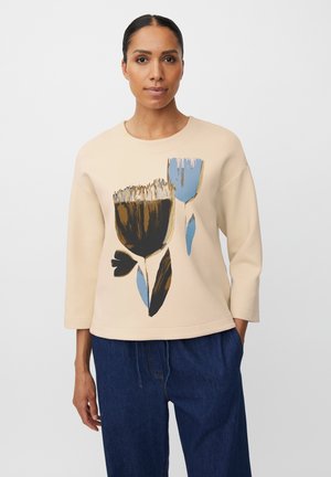 Beżowy sweter z rękawami do trzech ćwiartek, z kwiatowym wzorem w brązie i niebieskim. Miękka faktura, luźny krój i okrągły dekolt.