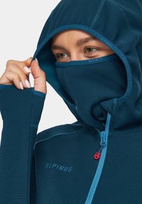 Turkusowy zip-up hoodie z dopasowanym kapturem i osłoną na twarz. Posiada teksturowany materiał oraz kontrastowy niebieski zamek błyskawiczny z czerwonym akcentem.