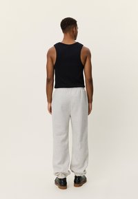 Μαύρο αμάνικο τοπ συνδυασμένο με γκρι ανοιχτό φόρμας παντελόνι. Το παντελόνι διαθέτει ελαστική μέση. Μαύρα παπούτσια με στιβαρή σόλα.