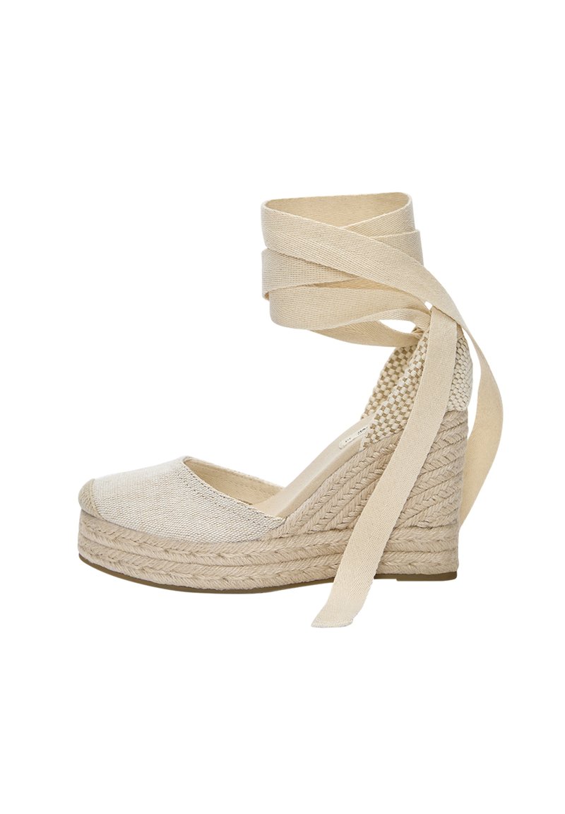 Beige espadrille-hæle med en tekstureret stofoverdel, jute-platform og lange stofbånd til anklene. Har en rund tå og vævet hældetalje.