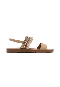 Tan flat sandal with a wide decorative strap featuring woven accents and metallic details. Open toe design with an adjustable back strap.