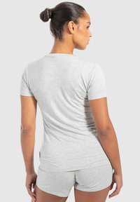 Grå kortærmet T-shirt med rund halsudskæring, lavet af blødt stof. Bagsiden har en tætsiddende design, parret med matchende shorts.