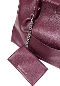 Borsa a tracolla in pelle testurizzata bordeaux con dettagli in catena argentata e portafoglio coordinato, dotata di chiusura con zip e rilievo del logo.