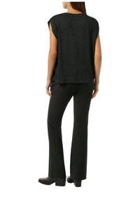 Czarna, krótko-sleeve bluzka o luźnym kroju z delikatnym blaskiem. Połączona z czarnymi, dzwonowymi spodniami i botkami na obcasie, tworzy monochromatyczny wygląd.