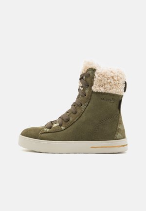 Green suede ankle boot with a cream faux fur collar, lace-up design, rubber sole, and subtle branding on the side.