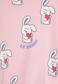 Pink fabric featuring multiple cartoon bunny illustrations, each holding a red heart, with the text "LE BUNNY" in blue above.