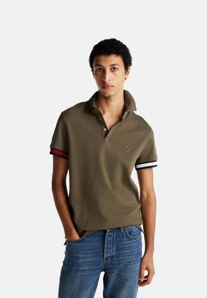 Camisa polo de color verde oliva con mangas cortas y acentos en franjas rojas, blancas y marinas. Cuenta con un cuello clásico y una tapeta de dos botones.