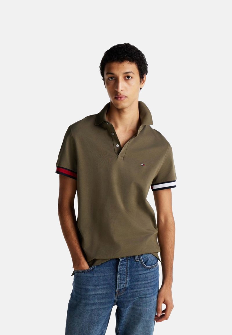 Camisa polo de color verde oliva con mangas cortas y acentos en franjas rojas, blancas y marinas. Cuenta con un cuello clásico y una tapeta de dos botones.