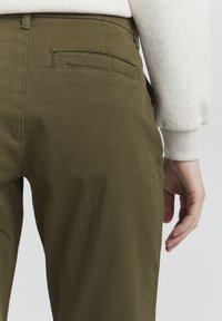 Olive green trousers with a straight cut, made of a durable fabric. Features a back pocket and a smooth texture. Visible stitching detail.