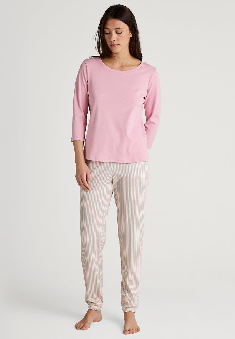 Lichtroze langwerpige top met een ronde hals, gecombineerd met gestreepte broek in wit, roze en groen. Zachte stof, aansluitende manchetten.