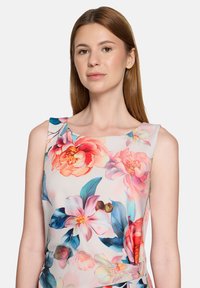 Robe fleurie en tissu léger avec de grandes fleurs roses et bleues, encolure carrée et design sans manches avec une texture lisse.