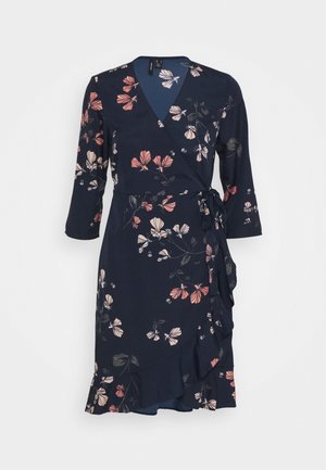 Marineblå omslagskjole med pink og hvidt blomsterprint, trekvartærmer, flæsekant og bindebælte i siden.