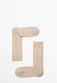 Beige gerippte Socken aus strukturiertem Stoff, mit verstärkter Spitze und Bündchen, so angeordnet, dass sie eine "L"-Form bilden.