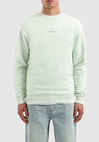 Lichtgroene crewneck sweatshirt van zacht materiaal, met een ribgebreide halslijn en manchetten, voorzien van de tekst "PURE PATH" in het midden.