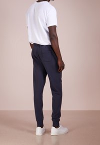 Vit bomull t-shirt med rullade ärmar, kombinerad med marinblå sweatpants med bakficka och ribbade muddar, kompletterad med vita sneakers.