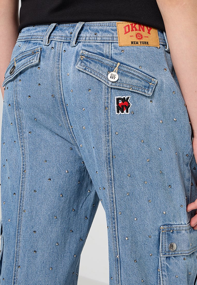 Hellblaue Jeans aus Denim mit einer strukturierten Oberfläche, silbernen Nieten, Cargo-Taschen und einem DKNY-Label am Bund.