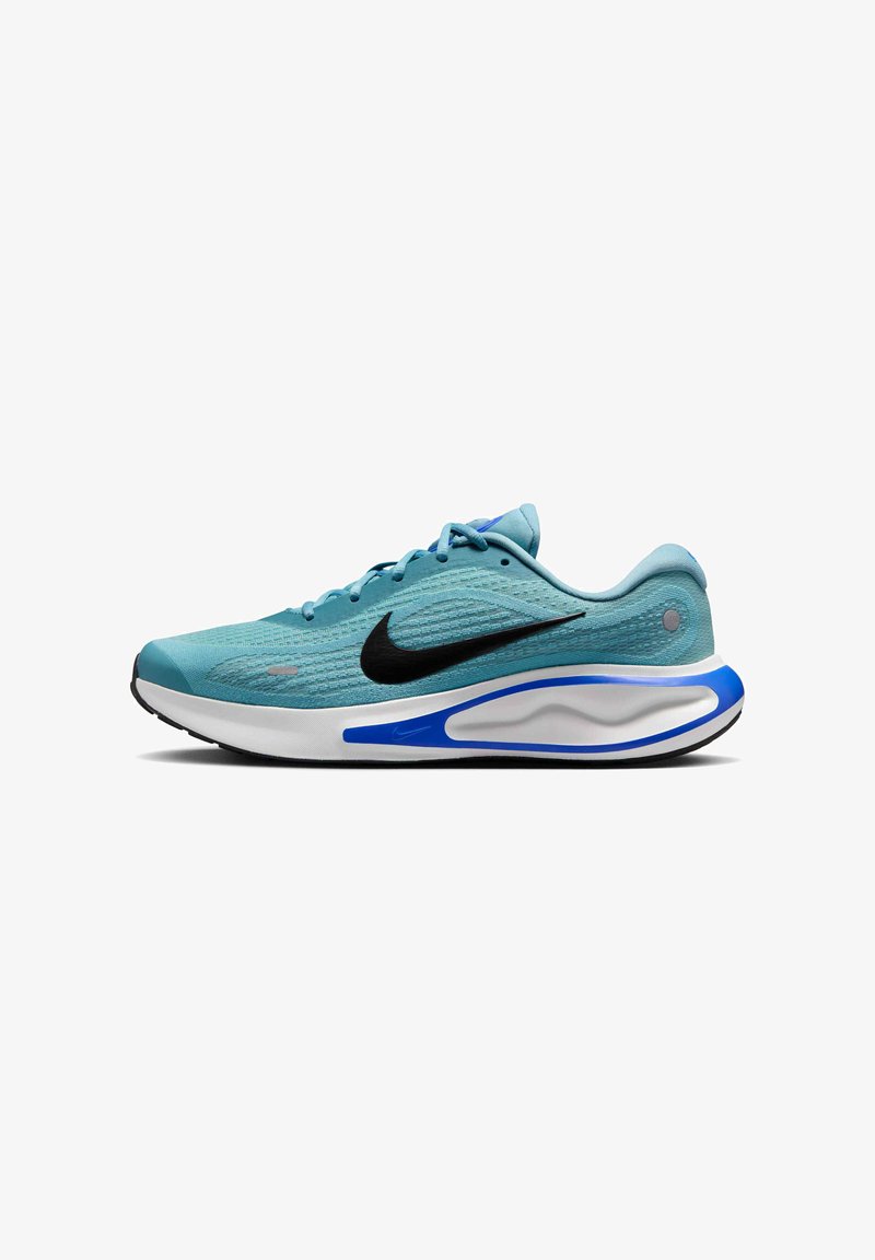 Shoe atlético de tom azul claro com parte superior em malha texturizada, swoosh preto, entressola branca e detalhe azul na sola. Forma contornada e cadarços visíveis.
